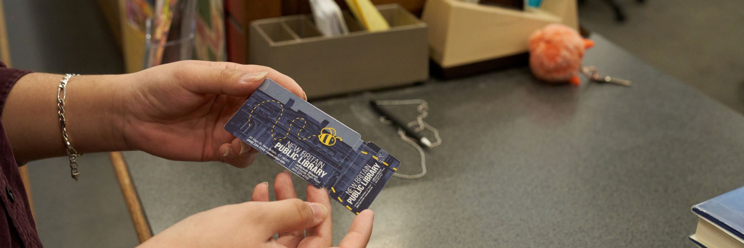 Closeup of person holding new library card at the circulation desk