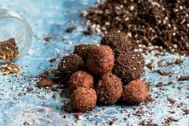 Brown balls of dirt and clay filled with seeds and stacked on a light blue background.