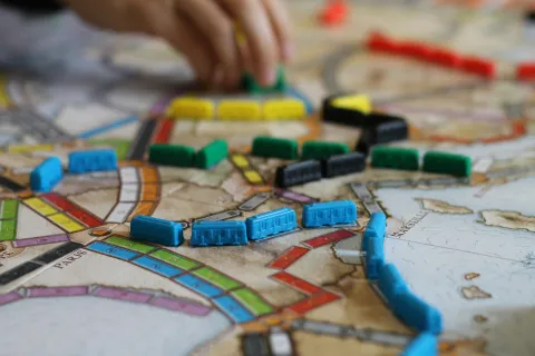 Image of board game map with small colorful pieces that look like trains on top